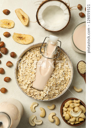 Bottles of milk, bowl with oatmeal and herbal ingredients on light background, top view Bottles of milk, bowl with oatmeal and herbal ingredients on light background, top view 126059321