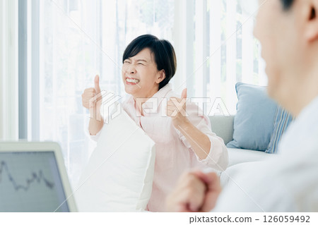 A middle-aged couple happily watching a computer in the living room A middle-aged couple happily watching a computer in the living room 126059492