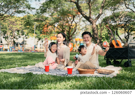 Happy family having a picnic and playing with bubbles together at the park Happy family having a picnic and playing with bubbles together at the park 126060607