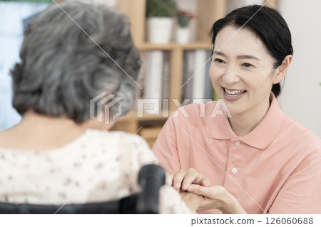 一位女性護理人員正在與一位坐在輪椅上的老年婦女交談 126060688