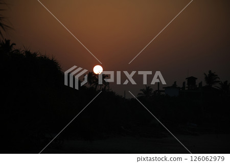 Behold the breathtakingly beautiful scene of a stunning sunset over silhouetted palm trees Behold the breathtakingly beautiful scene of a stunning sunset over silhouetted palm trees 126062979