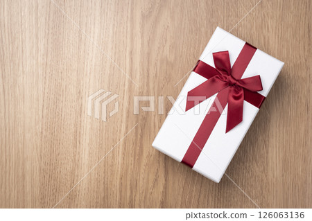 Overhead view of gift box with red ribbon on wooden table 126063136