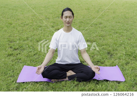 Young man doing yoga on the grass in the park Young man doing yoga on the grass in the park 126064216