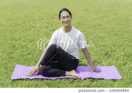 Young man doing yoga on the grass in the park Young man doing yoga on the grass in the park 126064664