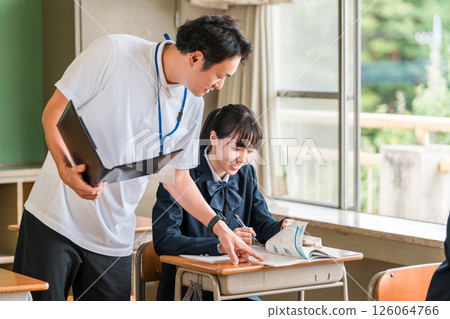 A male teacher and a female student teaching students in a school classroom 126064766