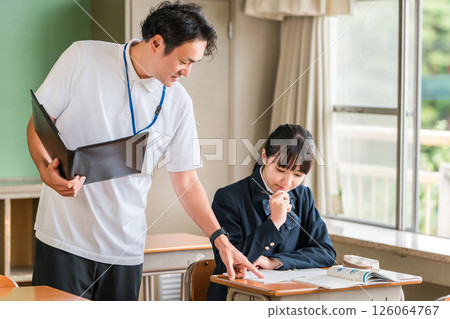 A male teacher and a female student teaching students in a school classroom 126064767