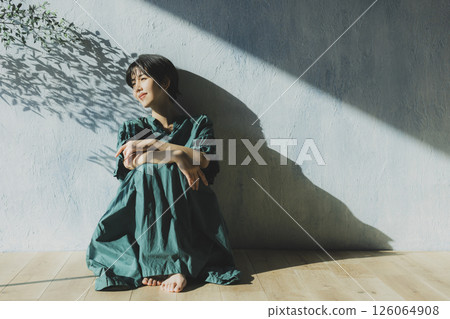 A young woman in a green dress leaning against a wall A young woman in a green dress leaning against a wall 126064908