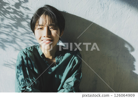 A young woman in a green dress leaning against a wall A young woman in a green dress leaning against a wall 126064909