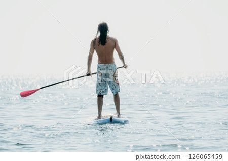Man Paddleboard Ocean - Man paddling on a paddleboard in the ocean. Man Paddleboard Ocean - Man paddling on a paddleboard in the ocean. 126065459
