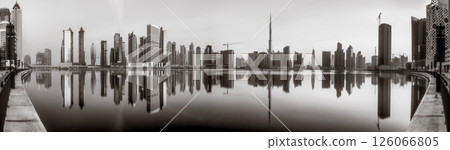 Monochrome city skyline with tall skyscrapers reflecting on calm water under a cloudy sky, Dubai Marina bay UAE Monochrome city skyline with tall skyscrapers reflecting on calm water under a cloudy sky, Dubai Marina bay UAE 126066805