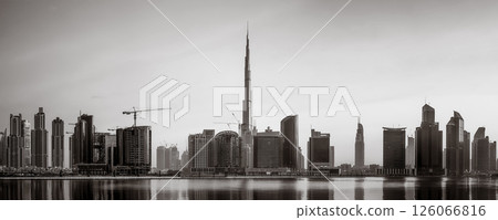 Monochrome city skyline with tall skyscrapers reflecting on calm water under a cloudy sky, Dubai Marina bay UAE Monochrome city skyline with tall skyscrapers reflecting on calm water under a cloudy sky, Dubai Marina bay UAE 126066816