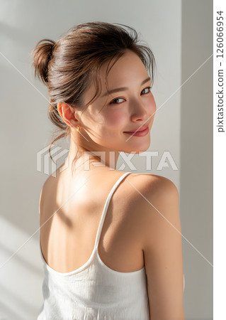 A smiling Japanese woman looking back. A natural portrait in soft natural light. 126066954