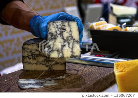 Seller slicing mold cheese on wooden board. Cheese shop. Seller slicing mold cheese on wooden board. Cheese shop. 126067207