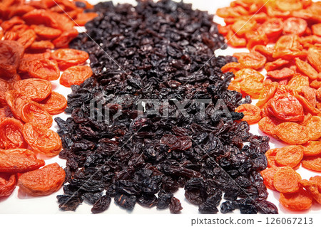 Orange dried apricots and dark raisins isolated on white background top view. Dried fruits background. 126067213