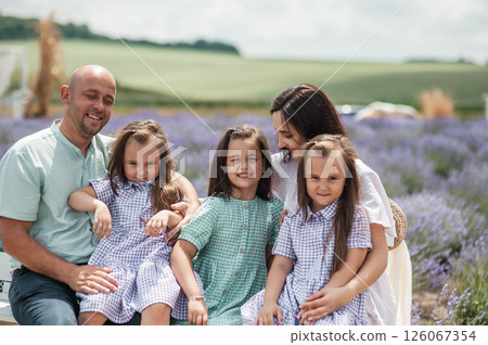 A beautiful family is resting in a lavender field. 126067354