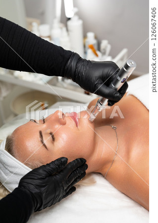 Microneedle RF lifting procedure. A cosmetologist performs a facial rejuvenation procedure on a woman. Hardware cosmetology. Microneedle RF lifting procedure. A cosmetologist performs a facial rejuvenation procedure on a woman. Hardware cosmetology. 126067406