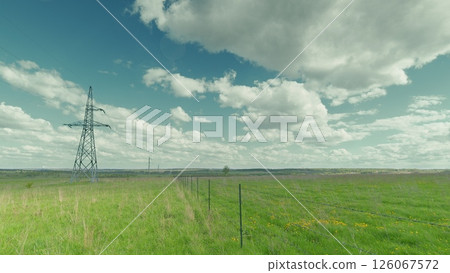 A vast and expansive green field adorned with power lines stretching under the sky above Time lapse. A vast and expansive green field adorned with power lines stretching under the sky above Time lapse. 126067572