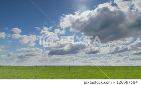 A Vibrant Green Field beautifully spreads out majestically under a dramatic, cloudy sky above it Time lapse. 126067584