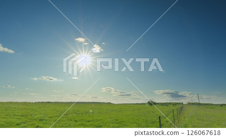 A vibrant and sunny day is unfolding over the lush green fields, creating a beautiful scene Time lapse. 126067618