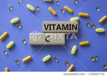 Vitamin C symbol. Concept word Vitamin C on wooden blocks. Beautiful purple background with pills. Medicine and Vitamin C concept. Copy space 126067729