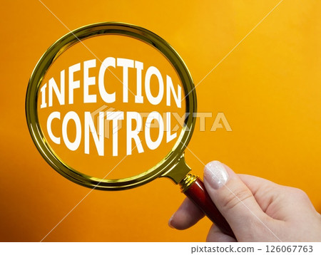 Infection Control symbol. Magnifying Glass with Concept word Infection Control. Businessman hand. Beautiful orange background. Business and Infection Control concept. Copy space 126067763