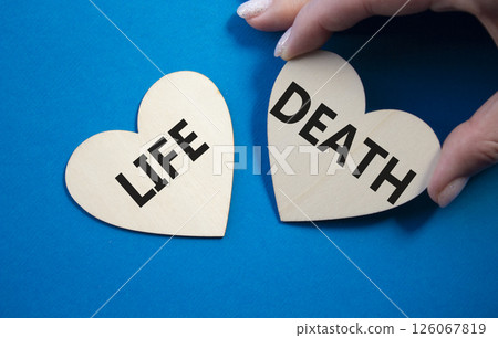 Life or Death symbol. Concept word Life or Death on wooden hearts. Businessman hand. Beautiful blue background. Business and Life or Death concept. Copy space Life or Death symbol. Concept word Life or Death on wooden hearts. Businessman hand. Beautiful blue background. Business and Life or Death concept. Copy space 126067819