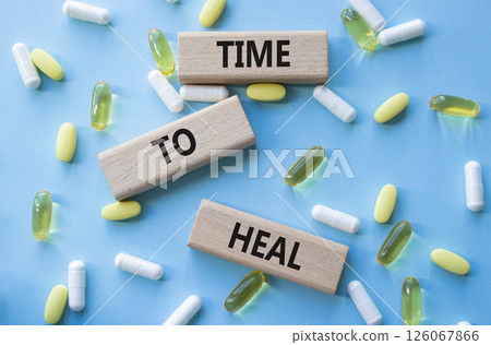 Medicine symbol. Concept words Time to Heal on wooden blocks. Beautiful blue background with pills. Medicine concept and Time to Heal. Copy space 126067866