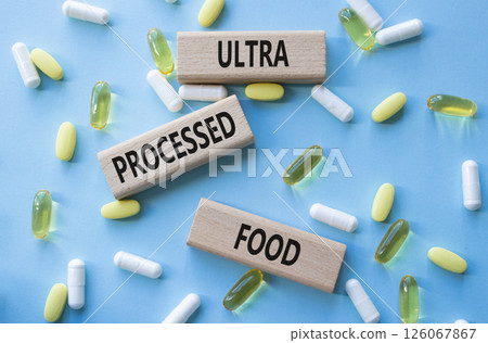 Medicine symbol. Concept words Ultra Processed Food on wooden blocks. Beautiful blue background with pills. Medicine concept and Ultra Processed Food. Copy space 126067867
