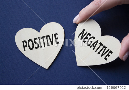 Positive or Negative symbol. Concept word Positive or Negative on wooden hearts. Businessman hand. Beautiful deep blue background. Business and Positive or Negative concept. Copy space 126067922