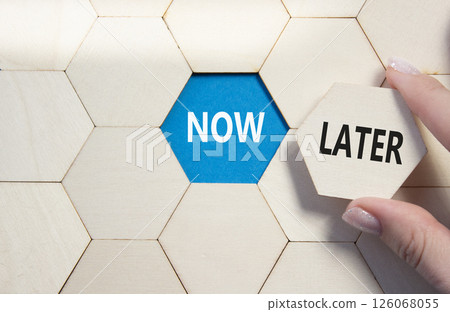 Now vs Later symbol. Concept word Now vs Later on wooden comb puzzle. Businessman hand. Beautiful blue background. Business and Now vs Later concept. Copy space 126068055