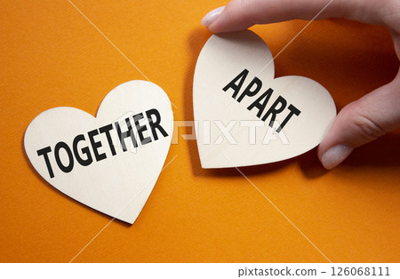 Together or Apart symbol. Concept word Together or Apart on wooden hearts. Businessman hand. Beautiful orange background. Business and Together or Apart concept. Copy space Together or Apart symbol. Concept word Together or Apart on wooden hearts. Businessman hand. Beautiful orange background. Business and Together or Apart concept. Copy space 126068111