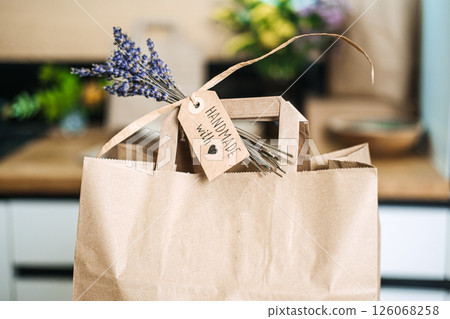 Close-up of a brown paper bag with a handwritten tag reading Handmade with love and a sprig of lavender. Handmade with love, emotional branding, artisan identity, heartfelt storytelling 126068258
