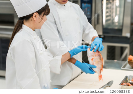 Male and female staff in chef coats preparing fish (chef, chef, fresh market, food processing) Male and female staff in chef coats preparing fish (chef, chef, fresh market, food processing) 126068388