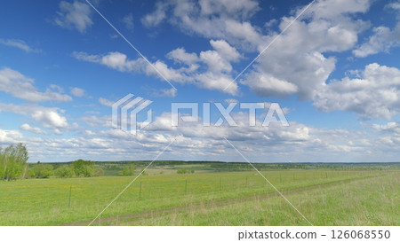A stunning and captivating panoramic landscape features a bright blue sky and vibrant green fields Time lapse. 126068550