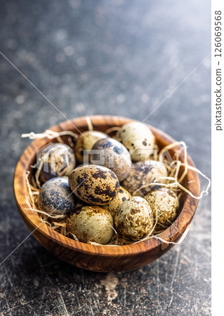Spotted quail eggs in bowl on black table. Spotted quail eggs in bowl on black table. 126069568