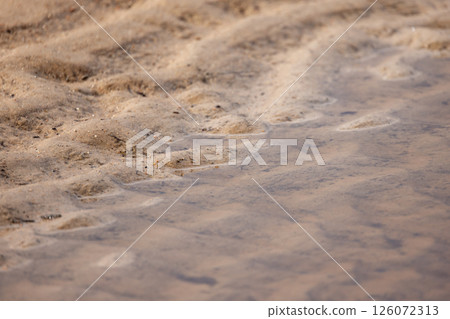 A detailed photograph showcasing ripples formed over a sandy surface A detailed photograph showcasing ripples formed over a sandy surface 126072313