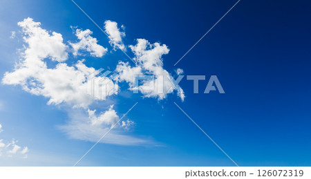A serene blue sky adorned with white, fluffy clouds floating tranquilly 126072319