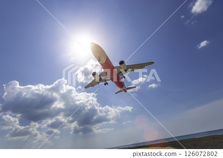 commercial airplane flight over the sea for landing at the airport on the tropical island, wide angle with light bokeh and blue sky at background. summer travel vacation concept commercial airplane flight over the sea for landing at the airport on the tropical island, wide angle with light bokeh and blue sky at background. summer travel vacation concept 126072802