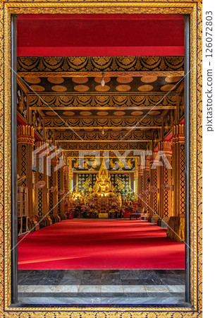 A view through the beautifully carved golden temple door frame shows a large Buddha statue inside a beautifully decorated chapel at Wat Phan On Temple, a popular landmark for tourists in Chiang Mai A view through the beautifully carved golden temple door frame shows a large Buddha statue inside a beautifully decorated chapel at Wat Phan On Temple, a popular landmark for tourists in Chiang Mai 126072803