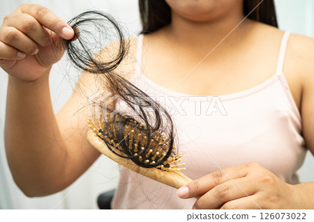 Asian woman have problem with long hair loss attach to comb brush. Asian woman have problem with long hair loss attach to comb brush. 126073022