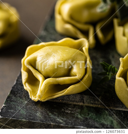 Fresh Tortellini with Ricotta and Spinach on Dark Green Background Fresh Tortellini with Ricotta and Spinach on Dark Green Background 126073631