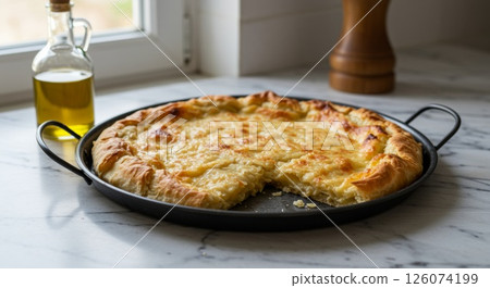 Homemade cheesy Greek pasta pie in round metal pan on marble windowsill with olive oil bottle Homemade cheesy Greek pasta pie in round metal pan on marble windowsill with olive oil bottle 126074199