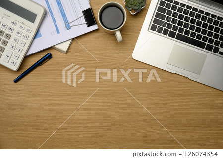 Modern office desk with laptop, calculator, coffee, and financial documents 126074354