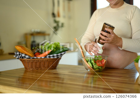 Pregnant woman preparing a fresh vegetable salad in the kitchen 126074366