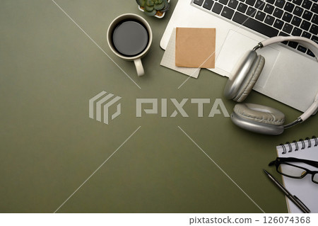 Flat lay of stylish desktop with laptop, coffee cup, headphones, and planner on green desk Flat lay of stylish desktop with laptop, coffee cup, headphones, and planner on green desk 126074368
