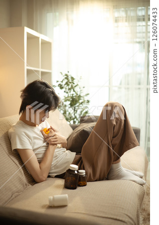 Man dealing with emotional pain and depression at home surrounded by medication 126074433