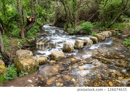 Walking across a bridge of stones over a stream at Percurso Pedestre de Galegos 126074635