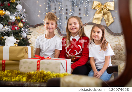 Two girls and boy on sofa in Christmas interior 126074668
