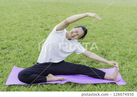 A young man stretching on the grass in a park and looking distressed 126074930