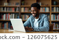 E-learning concept. Young African American guy in casual outfit student with computer laptop taking notes, attending webinar, online lesson 126075625